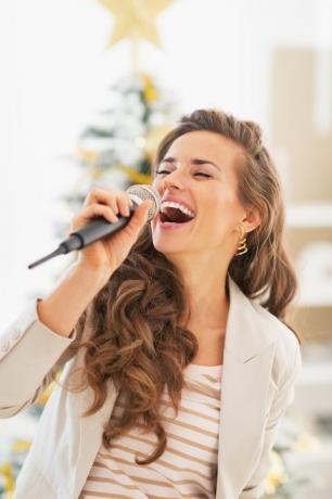 glad ung kvinne som synger foran juletre