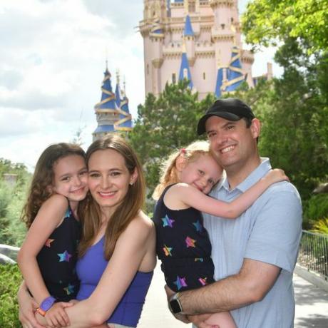 en familie smilende foran askepott-slottet i magic kingdom park