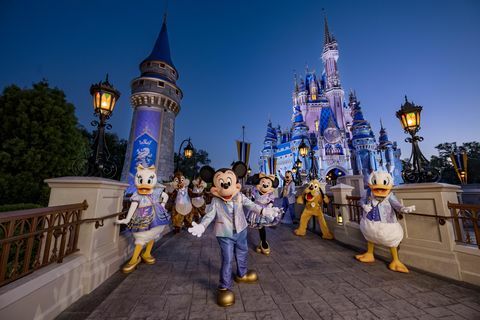 mickey mouse og venner iført 50-årsjubileet sitt glitrende mote mens de poserer foran askepottslottet i magic kingdom park